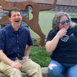 andy roark and stephanie goss laughing together by a fountain