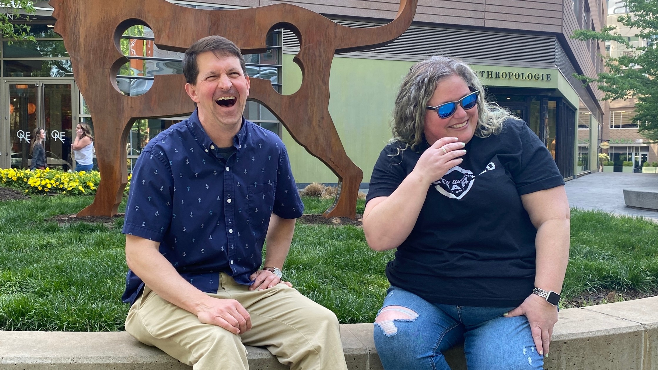 andy roark and stephanie goss laughing together by a fountain