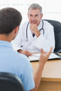 Attentive doctor listening to his patient in bright surgery