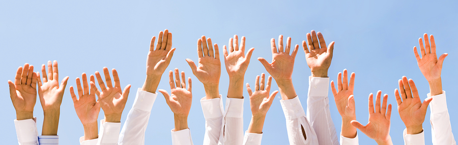 Close-up of several human hands raised against cloudy sky